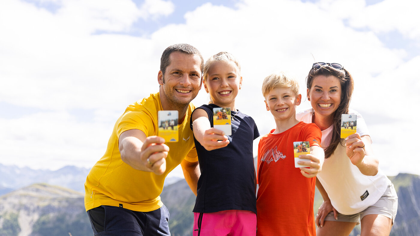 Familie zeigt die Super Sommer Card mit Bergpanorama im Hintergrund.
