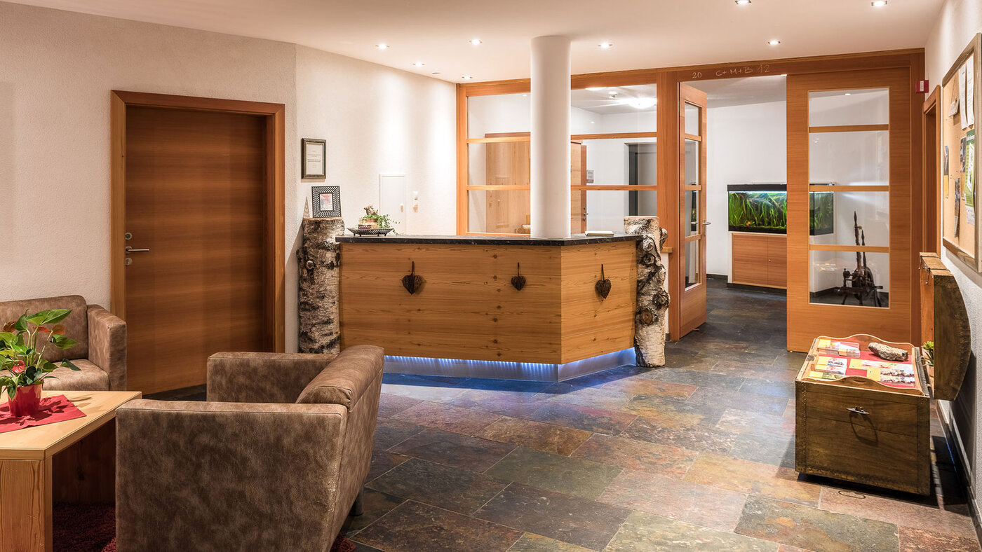 Rezeption mit Holztheke und Sitzbereich im Eingangsbereich eines Apartmenthauses.