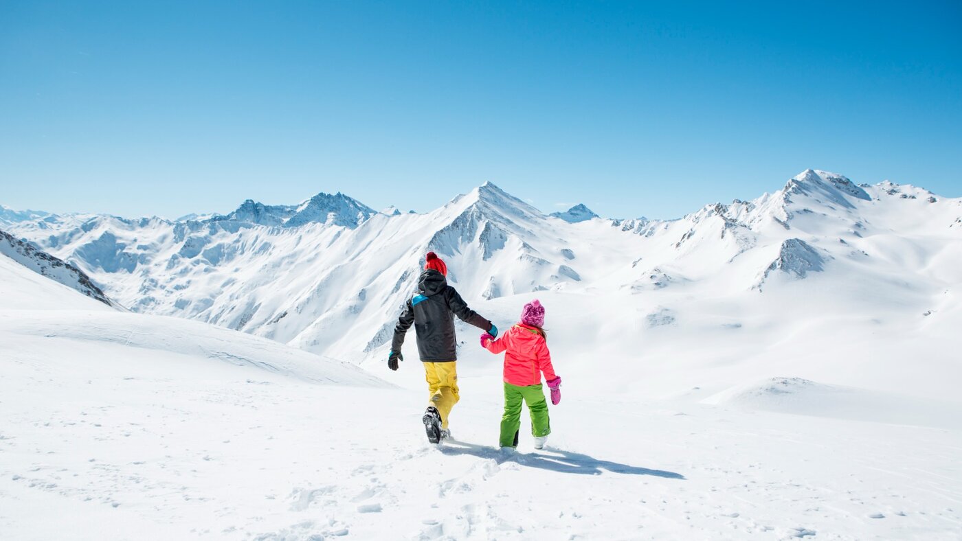 Familie mit Kindern auf Skipiste im Skigebiet Serfaus-Fiss-Ladis mit Alpenpanorama.